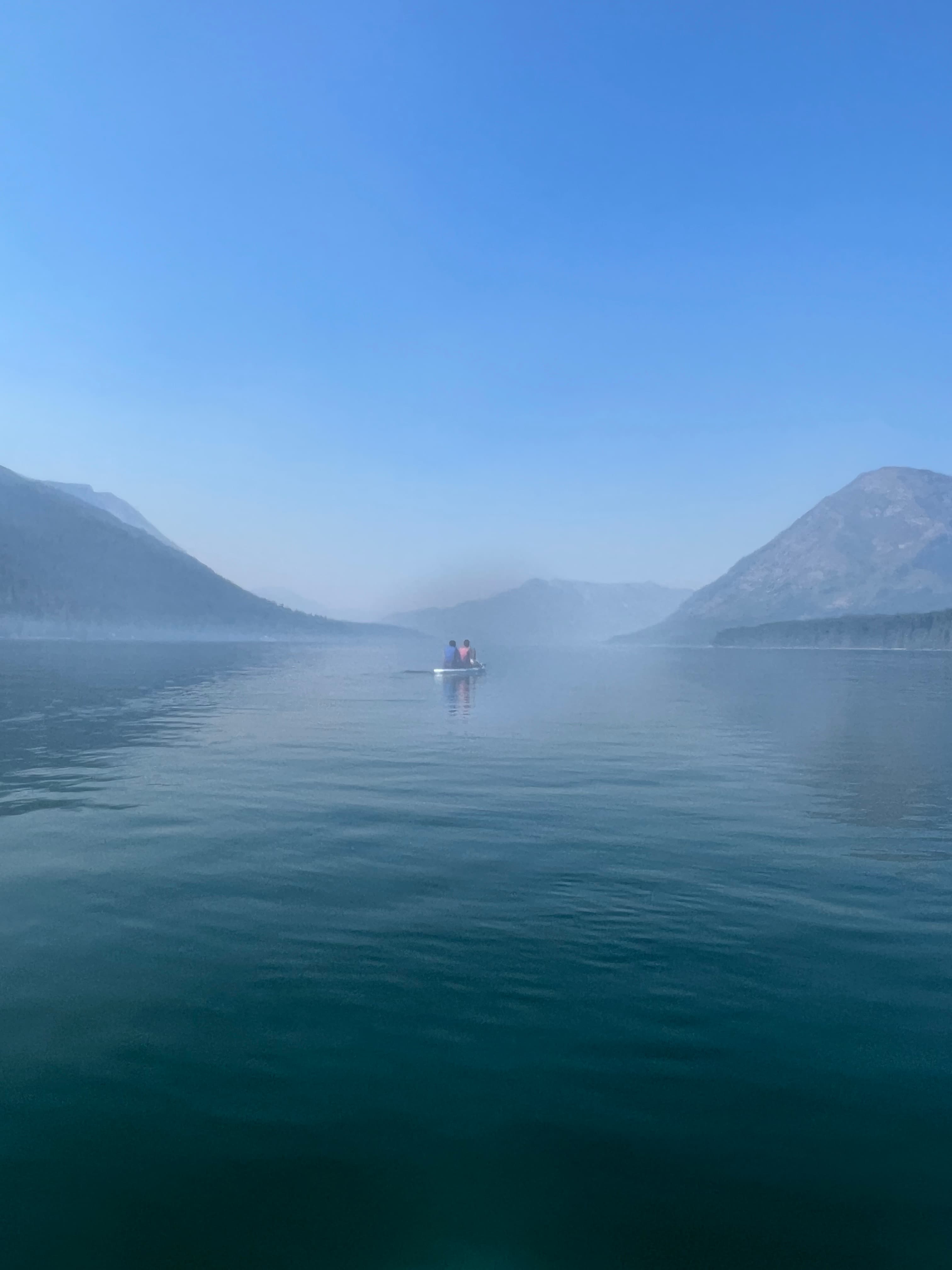 Misty lake framed by mountains.